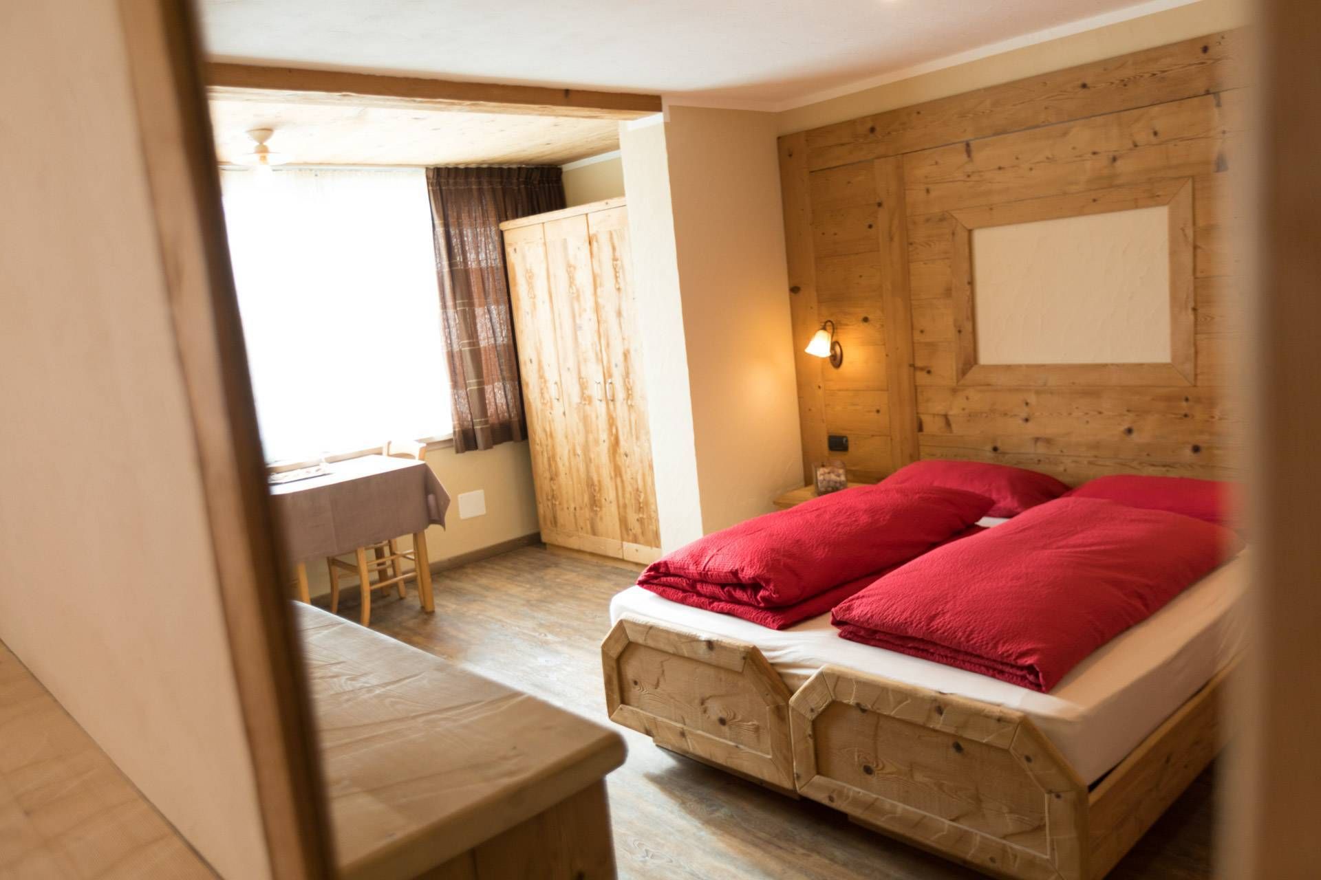 Camera con letti dai piumoni rossi e pareti rivestite in legno