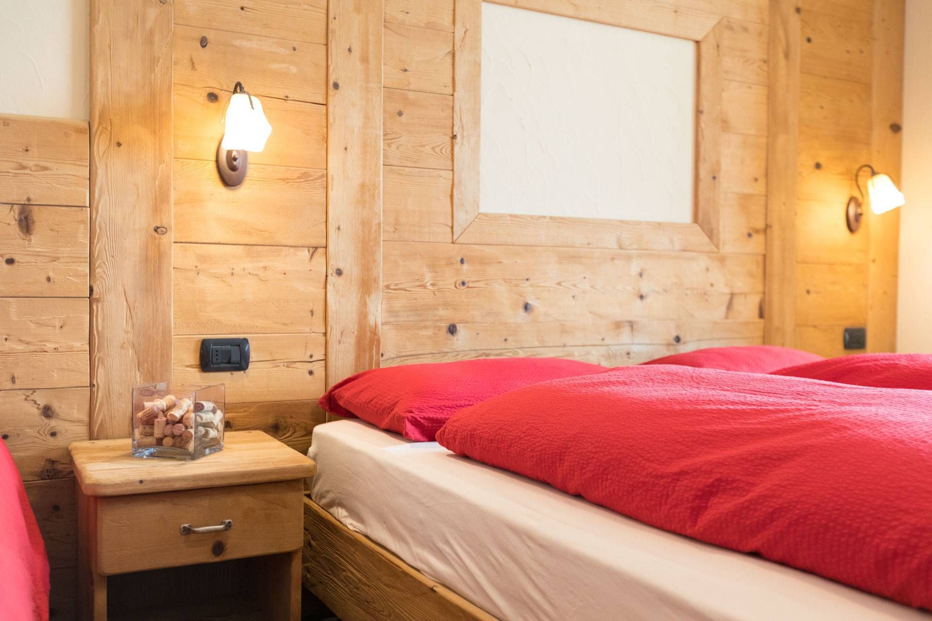 Letti con piumone rosso e comodino in legno