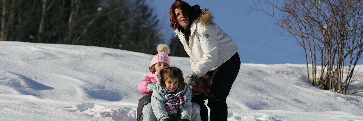 Mamma con due bambine che giocano sulla neve