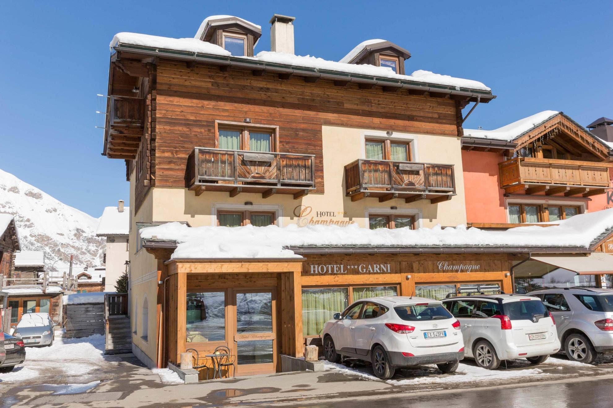 Facciata dell’Hotel Champagne con balconi in legno e parcheggio sotto la neve