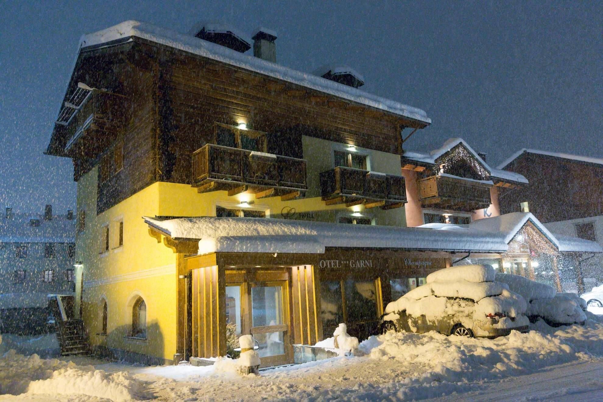 Hotel Champagne illuminato di sera durante una nevicata