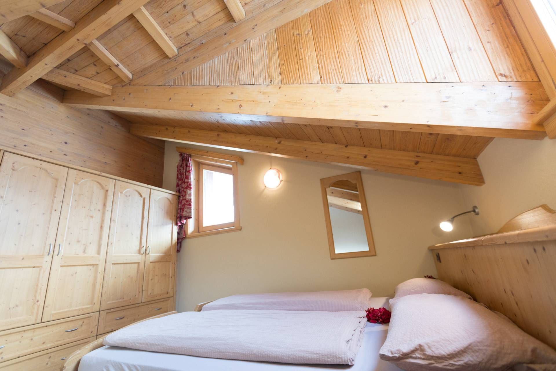 Armadio in legno e letto sotto le travi a vista