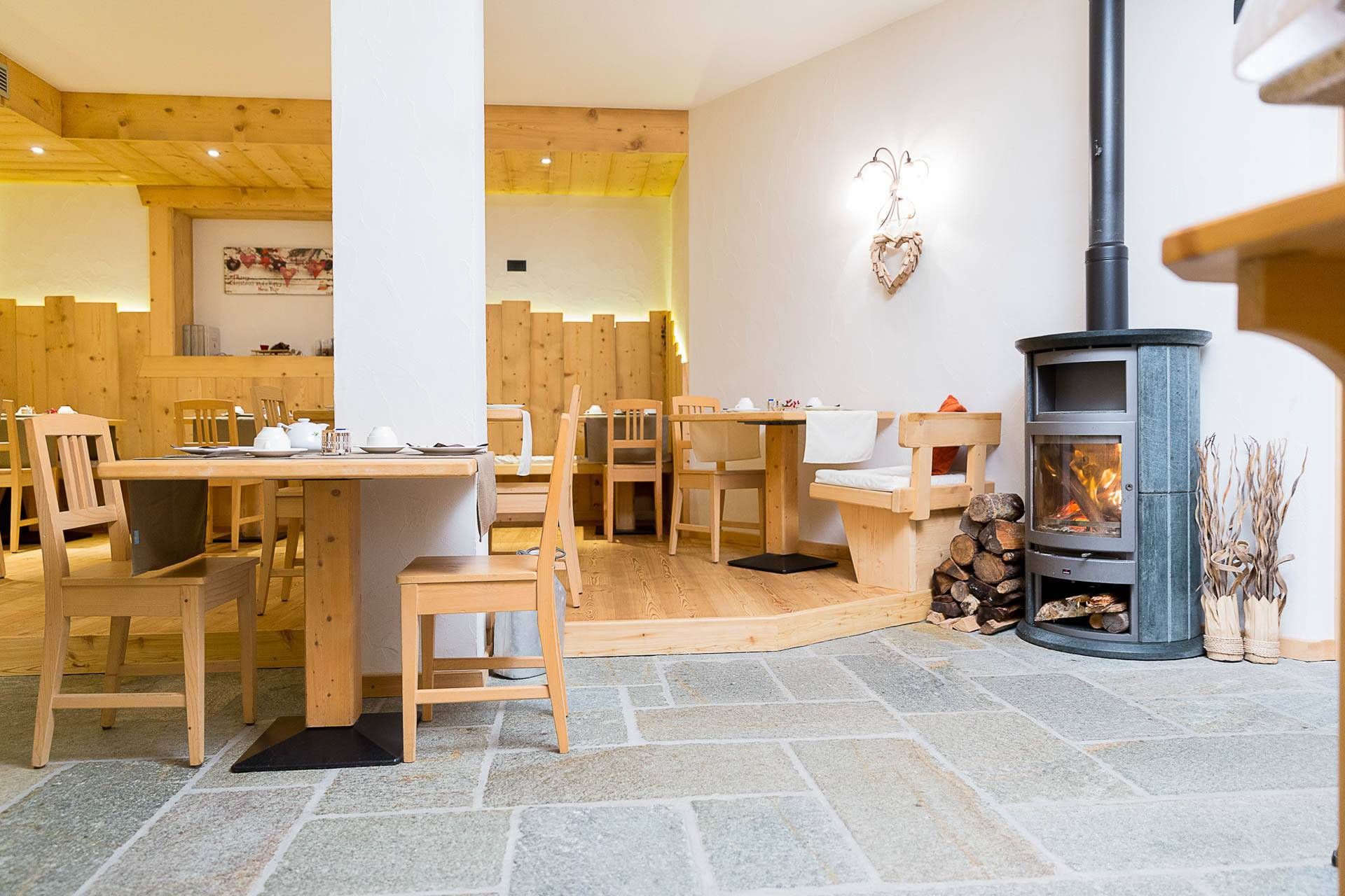 Sala colazione con stufa a legna e tavoli in legno chiaro